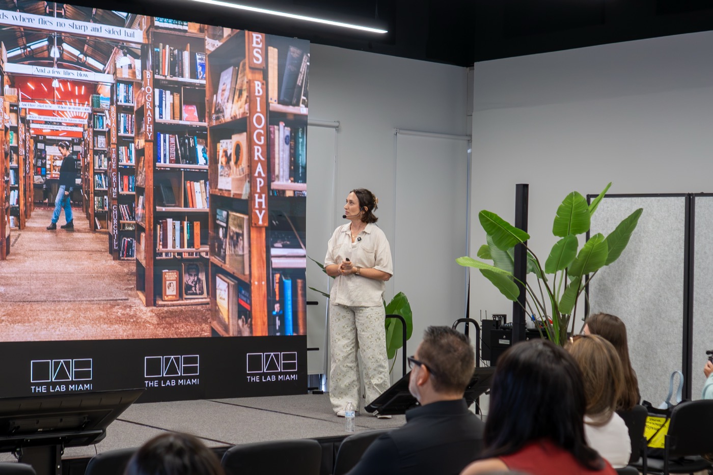 Cassie McDaniel presenting in front of a bookshop photograph